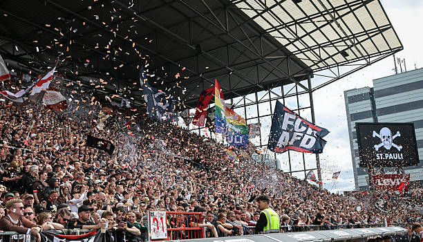 Foto da torcida do St.Pauli no jogo contra o Stuttgart, em maio de 2025. É possível ver bandas de protesto contra o partido de extrema direita da Alemanha (AFD) e a bandeira LGBTQIAPN+, ambas partes da identidade do St.Pauli. Foto: Christian Charisius/picture-alliance — Reprodução.