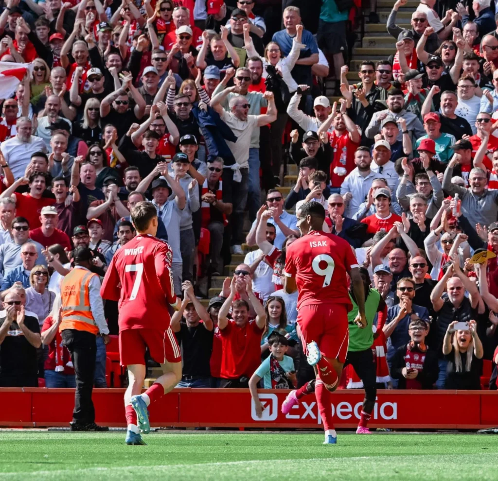 Wirtz e Isak celebram juntos. Detalhe para a comemoração efusiva da torcida ao fundo. Foto: Divulgação/Liverpool FC