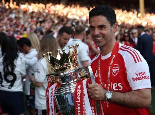 Arteta segurando taça da Premier League de 2025/26, conquistada pelo Arsenal
